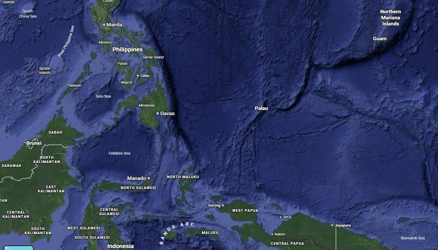 Satellite map of the western Pacific showing the Philippines with Manila, Cebu, Davao and Mindanao at the upper left, Indonesia and West Papua along the bottom, Palau in the centre and Guam and the Northern Mariana Islands to the upper right, with the deep ocean between them